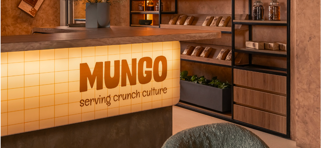 Mungo cafe counter with warm orange tile front, illuminated signage, and curated retail shelving