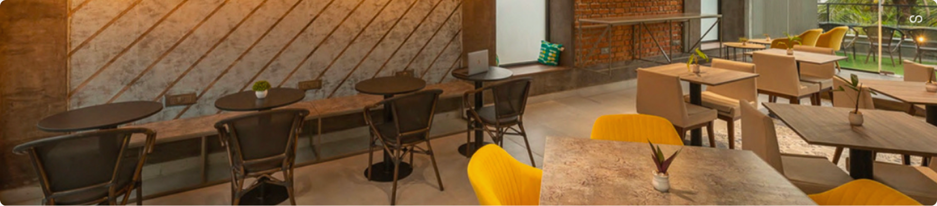 Cafe Grey — panoramic café interior with wood tables, yellow chairs, brick wall, and outdoor terrace views