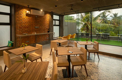 Cafe with exposed brick, patterned tile floor, and glass doors to a palm-lined terrace
