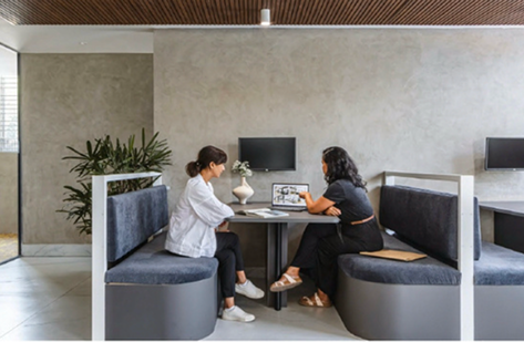Two people in a modern meeting booth with concrete wall and wood-slat ceiling