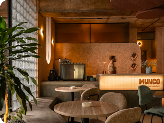 Mungo brunch cafe interior with glass block wall, bouclé seating, warm plaster walls, and glowing counter signage